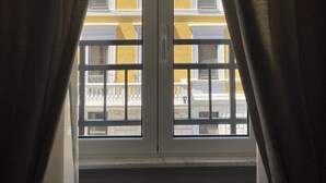 A window with two curtains, revealing a balcony with railings and a building facade. - De Vince Luxury Suites - Roma Termini (Rome)