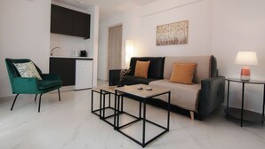 A modern living room with a green chair, a sofa, a coffee table, and a side table with a lamp. - Phaedrus Living: Skiathos Luxury Residences Lime (Skiathos)