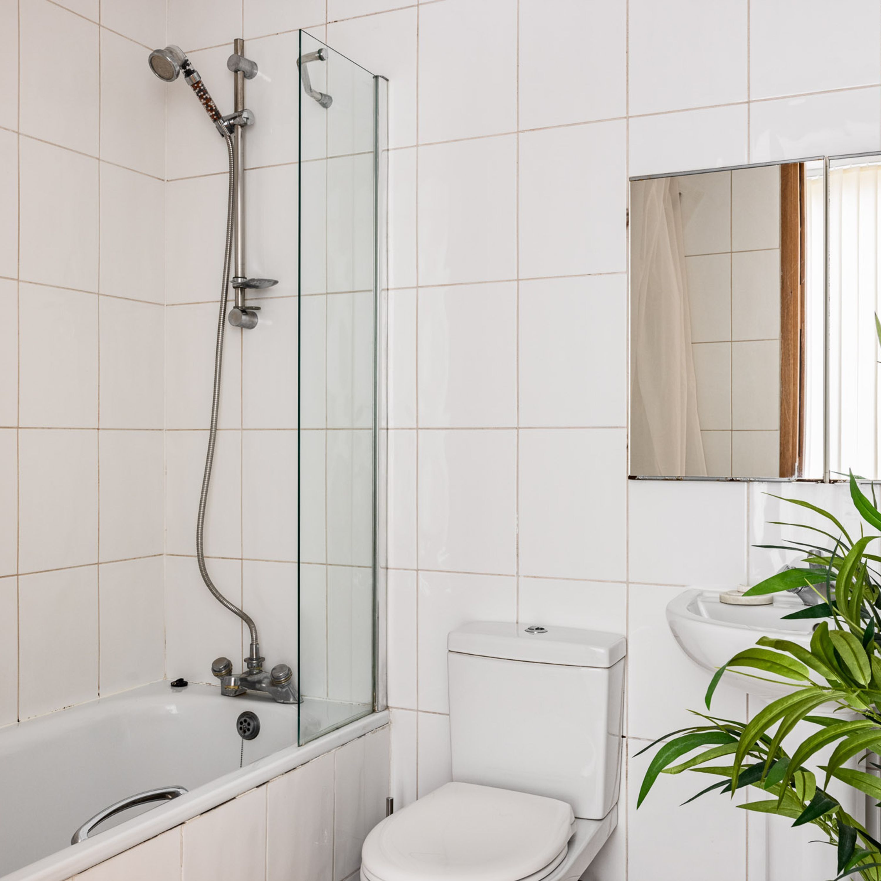 A bathroom with a glass-enclosed shower, a white toilet, and a sink with a mirror above it.