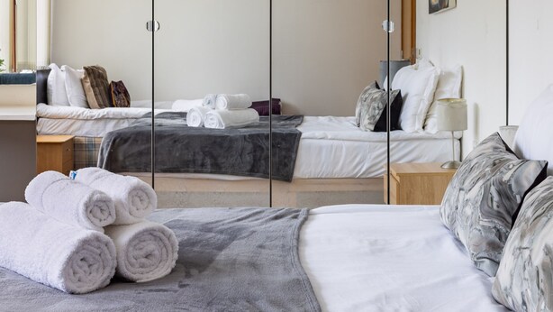 Ein Hotelzimmer mit einem großen Bett, einem kleineren Bett, einem Schreibtisch und einem Kleiderschrank.