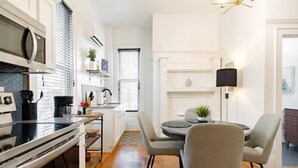 Une cuisine moderne avec un coin repas, comprenant un îlot central, une lampe noire et une vue sur le salon.