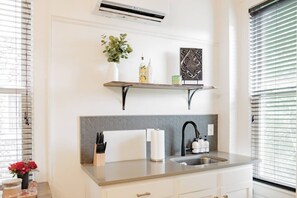 A kitchen with a built-in sink, a backsplash, and a window with blinds.