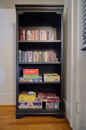 Una estantería con varios libros y juegos de mesa.