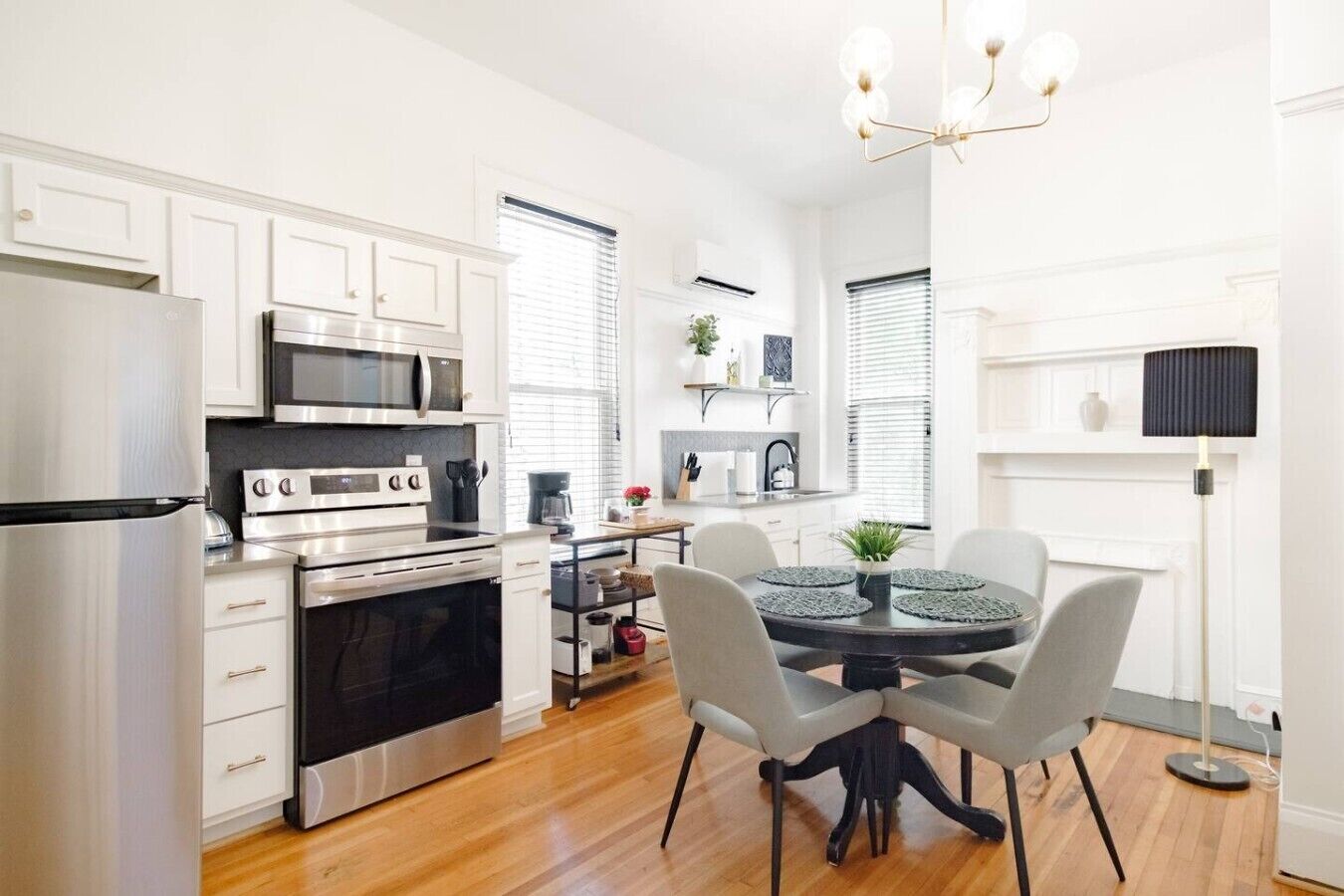 Una cocina moderna con electrodomésticos de acero inoxidable, un comedor con una mesa redonda y sillas, y una araña.