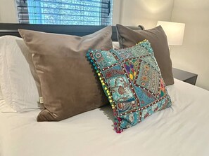 A bed with multiple pillows, including a decorative one with tassels.