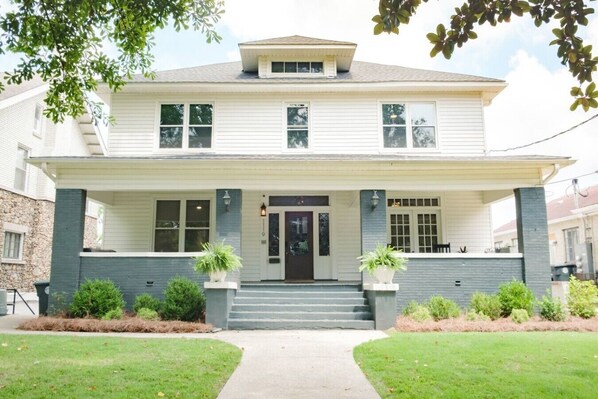 A two-story house with a front porch, a central entrance, and a small front yard.