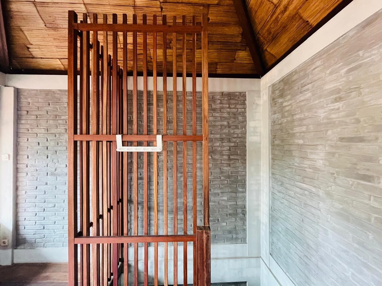 A room with a wooden partition, brick walls, and a sloped ceiling.
