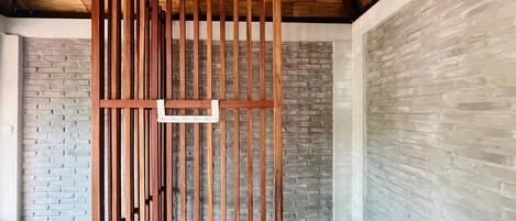 A room with a wooden partition, brick walls, and a sloped ceiling.