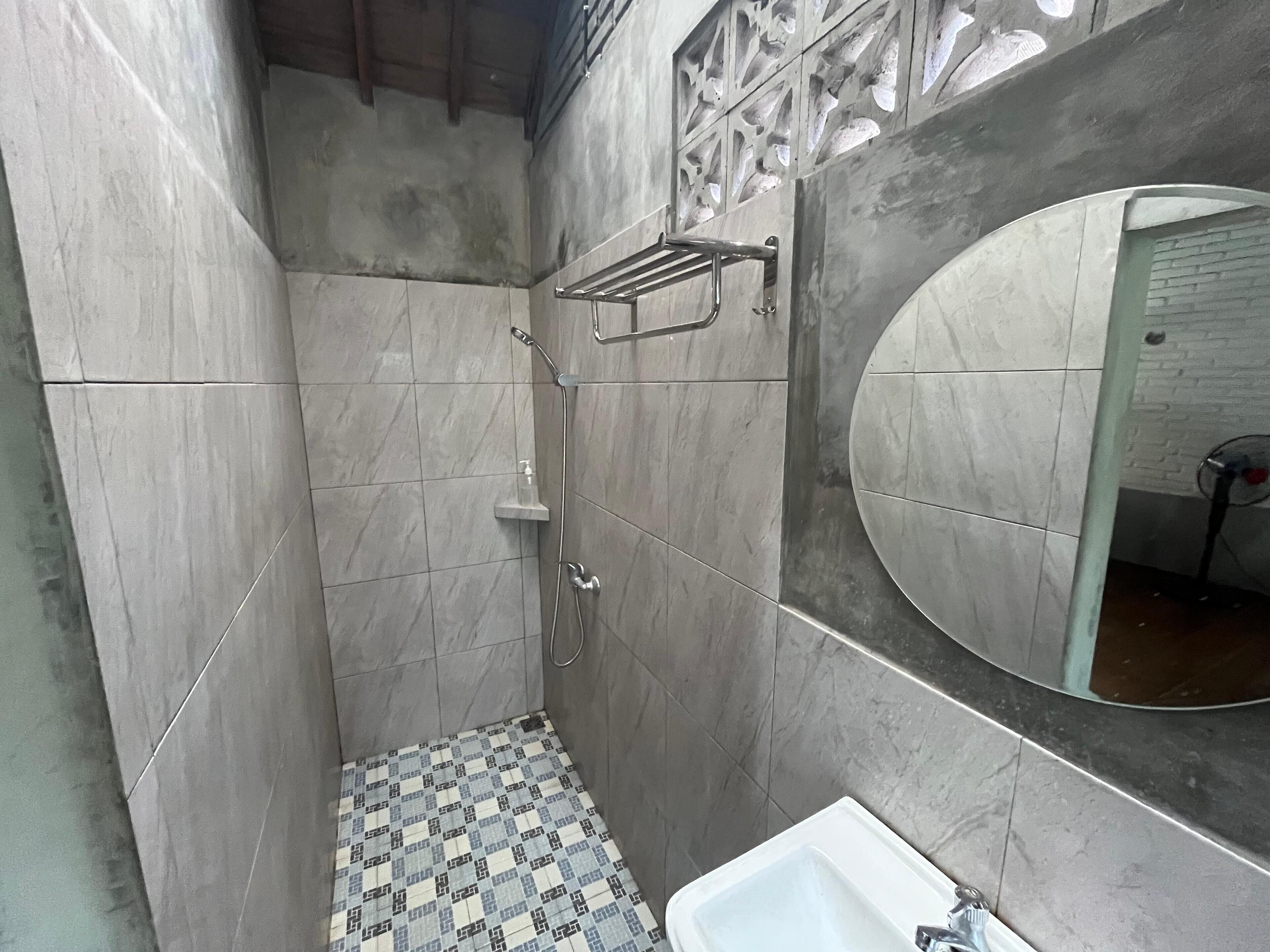 A small, tiled bathroom with a shower, a sink, and a mirror.