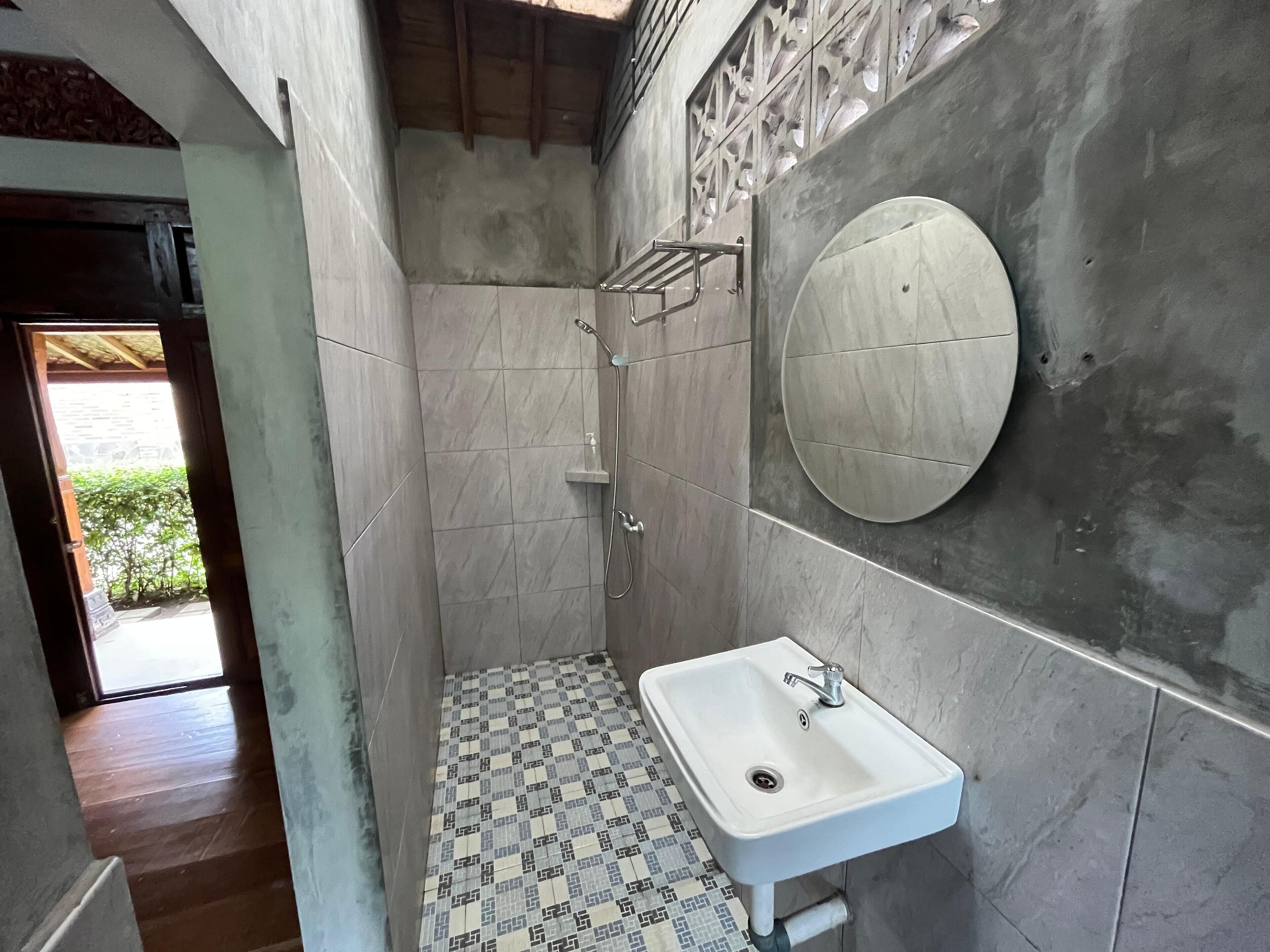 A bathroom with a shower, a sink, and a mirror.