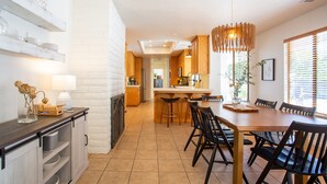 A modern kitchen with white brick walls, wooden cabinets, and a central island with stools. - Heated pool, hot tub, arcade, walk to town (Los Alamos)