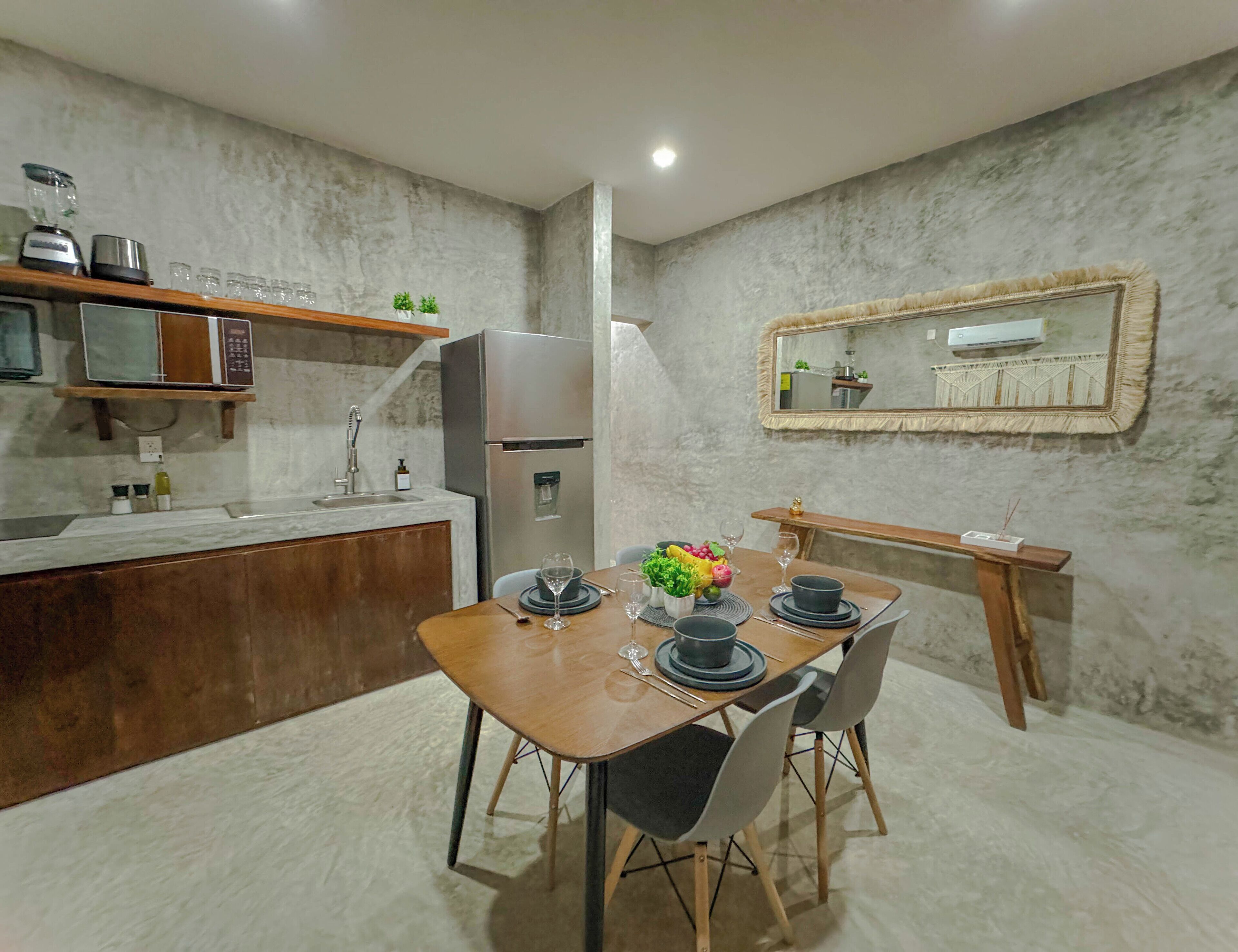 A modern kitchen with a wooden dining table, chairs, and a built-in refrigerator.