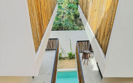 A pool with a view of the surrounding greenery, surrounded by white walls and wooden accents.