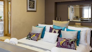 Ein Hotelzimmer mit Bett, Kissen, einem Spiegel und einem gerahmten Bild an der Wand.