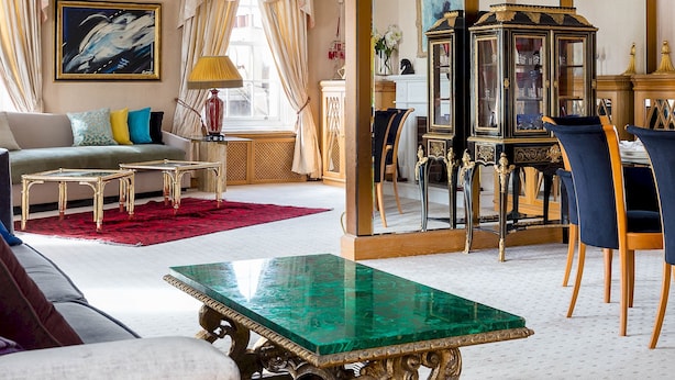 Ein geräumiges Wohnzimmer mit einem grünen Marmortisch, einer Couch und einem Essbereich mit Stühlen und einem Schrank.