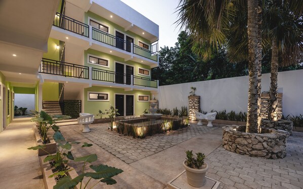 A modern multi-story building with a courtyard, stone walls, and outdoor seating. - Hotel Kuxtal (Valladolid)