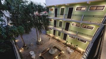 Un immeuble à plusieurs étages doté d’une cour intérieure comprenant une fontaine centrale, des sièges et des plantes en pot.