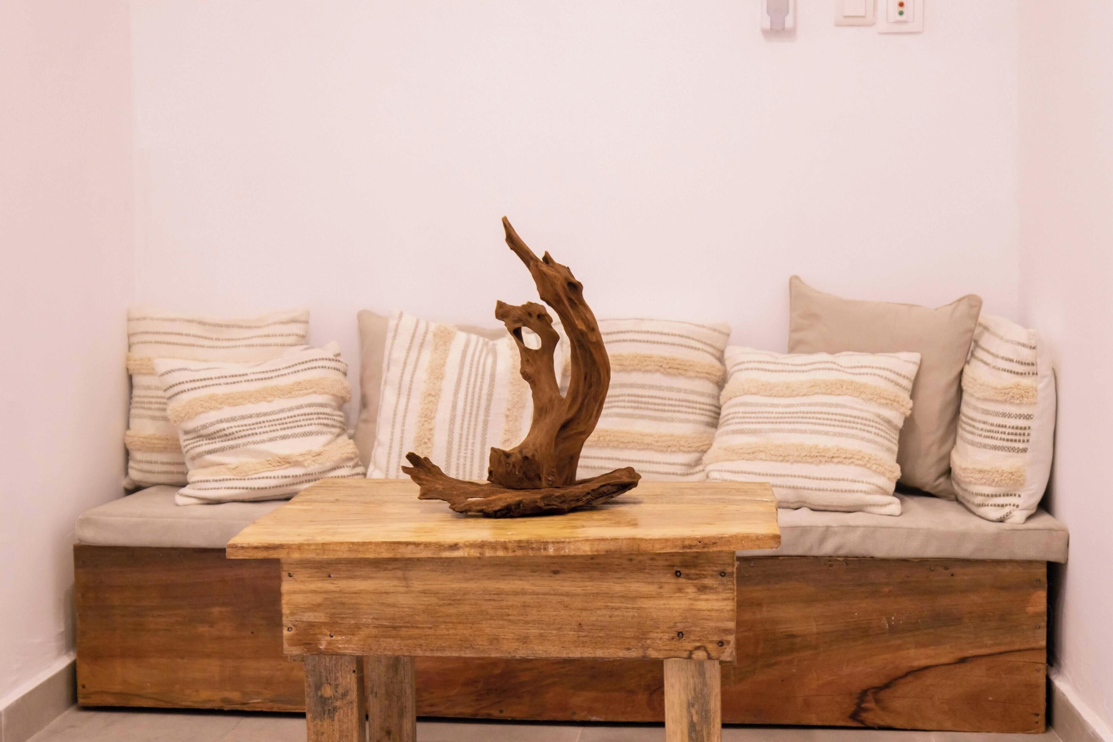 A wooden table with a unique branch centerpiece, placed in front of a sofa with striped pillows.