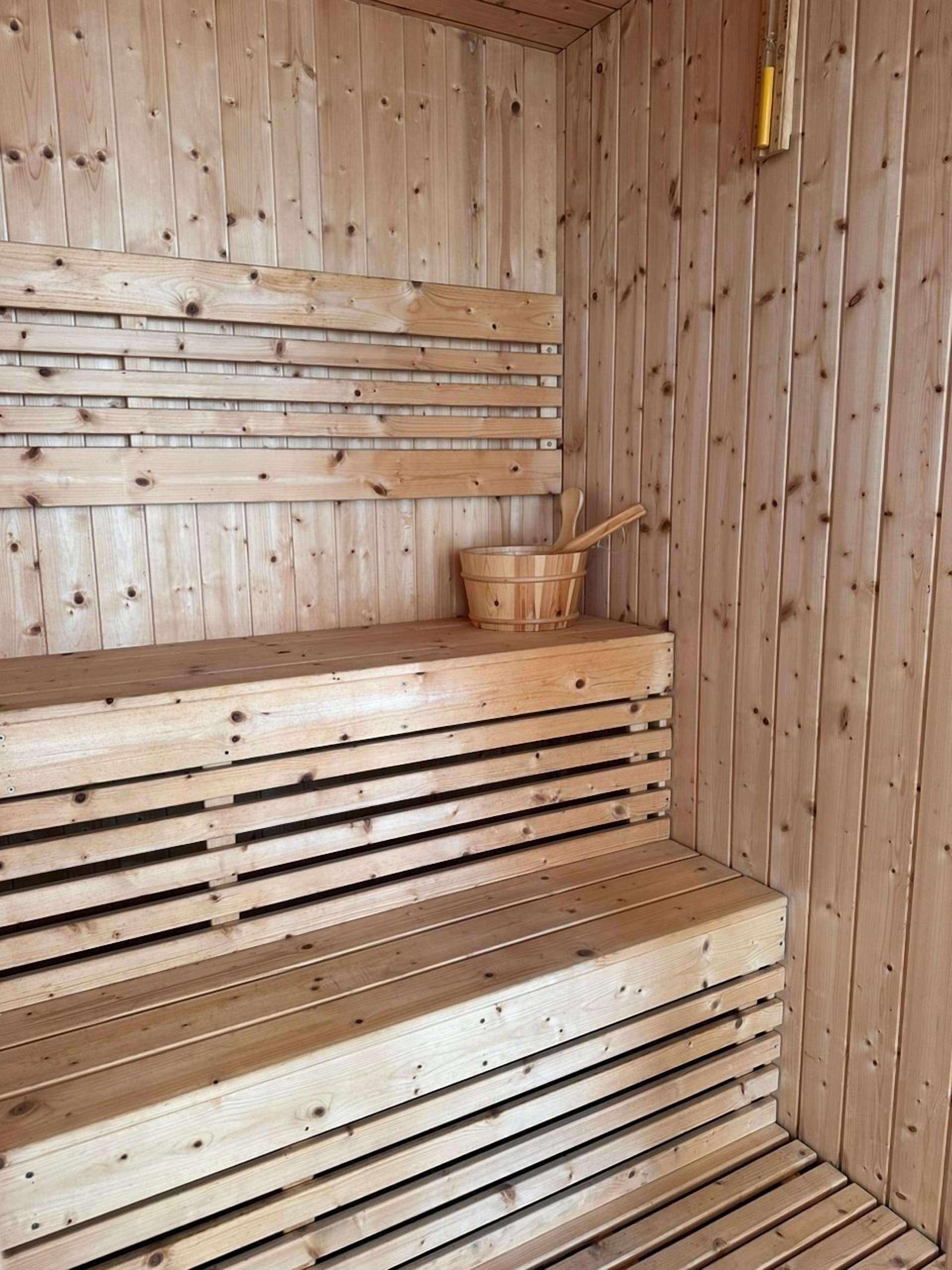 Un sauna en bois avec des bancs et un seau en bois.