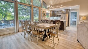 A spacious dining area with a wooden table and chairs, large windows offering a view of trees, and a modern kitchen with stainless steel appliances. - Tenkiller Lake Private Pickleball Court
Sleeps 20
Shuffleboard Pool Table
13Beds (Cookson)
