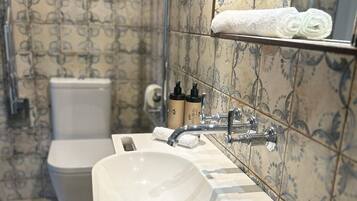 A bathroom with a toilet, two sinks, and a towel rack.