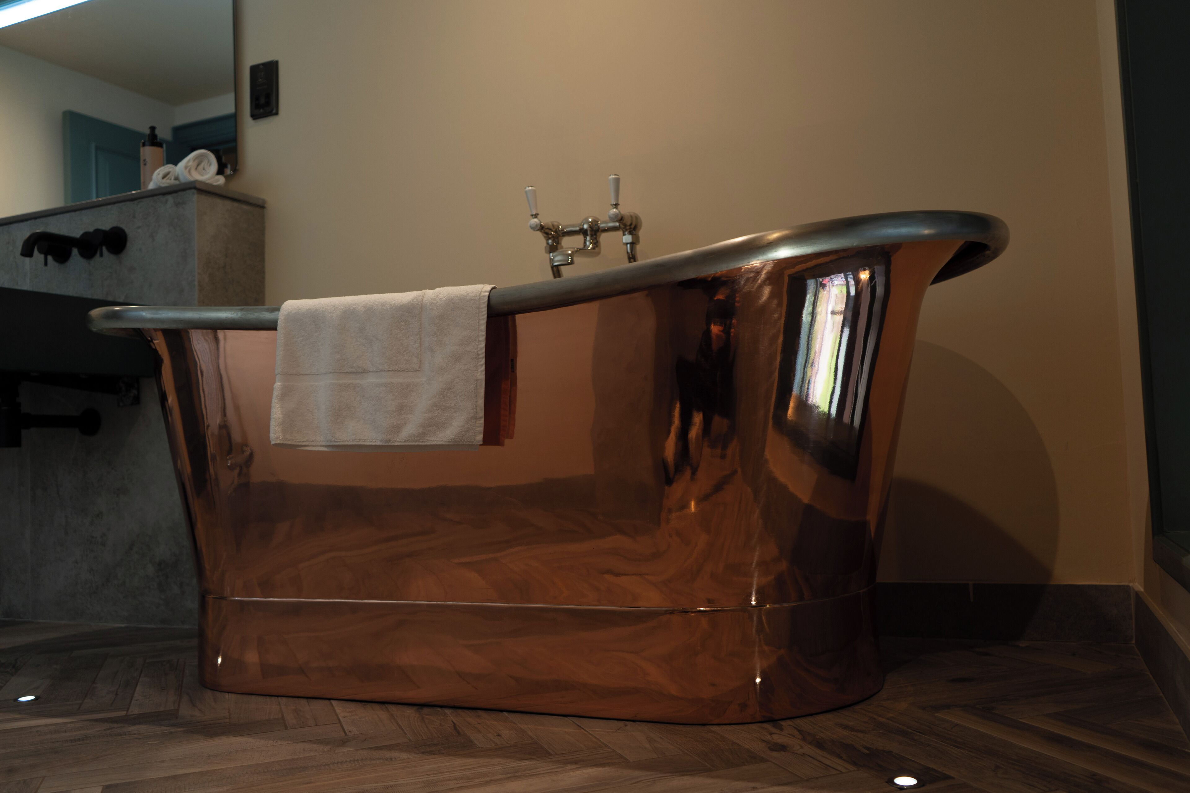 Un bagno moderno con una vasca freestanding, un asciugamano appeso a lato e una zona doccia visibile.