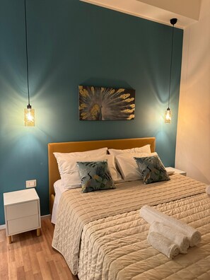 Ein Schlafzimmer mit einem Bett, zwei Kissen, einem Nachttisch und einem an der Wand befestigten Kunstwerk.