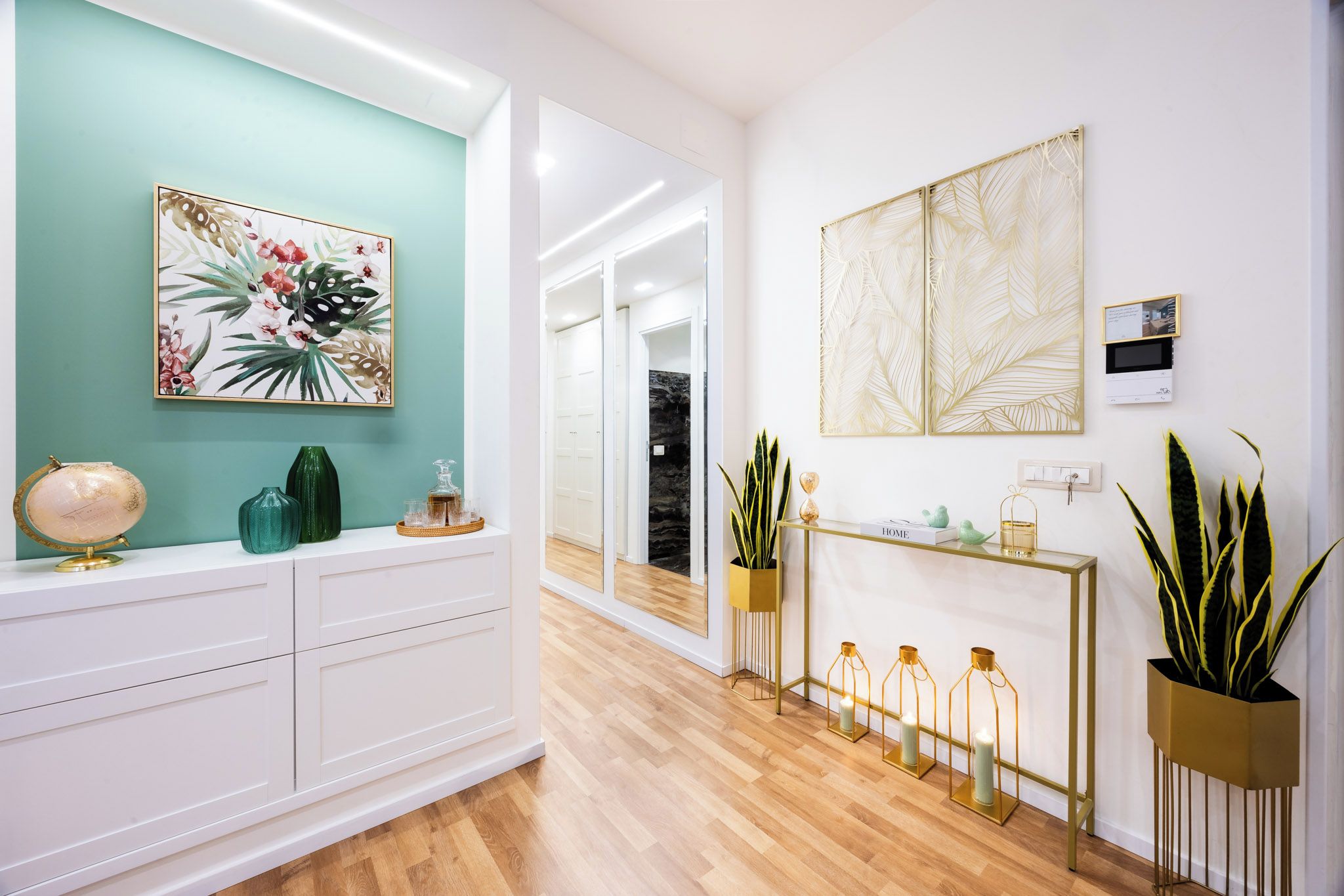 Ein modernes Interieur mit einer türkisfarbenen Akzentwand, einem weißen Konsolentisch mit Dekoration und einem Holzboden.