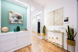 Ein modernes Interieur mit einer türkisfarbenen Akzentwand, einem weißen Konsolentisch mit Dekoration und einem Holzboden.