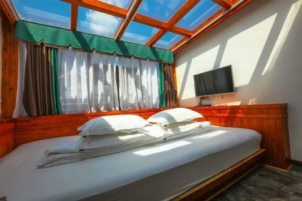 A room with a bed, a TV, and a skylight.