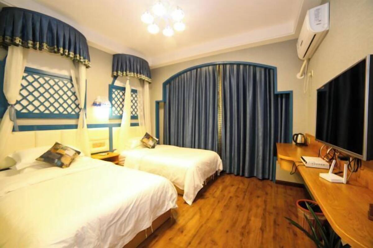A hotel room with two beds, a desk with a computer, and a TV.