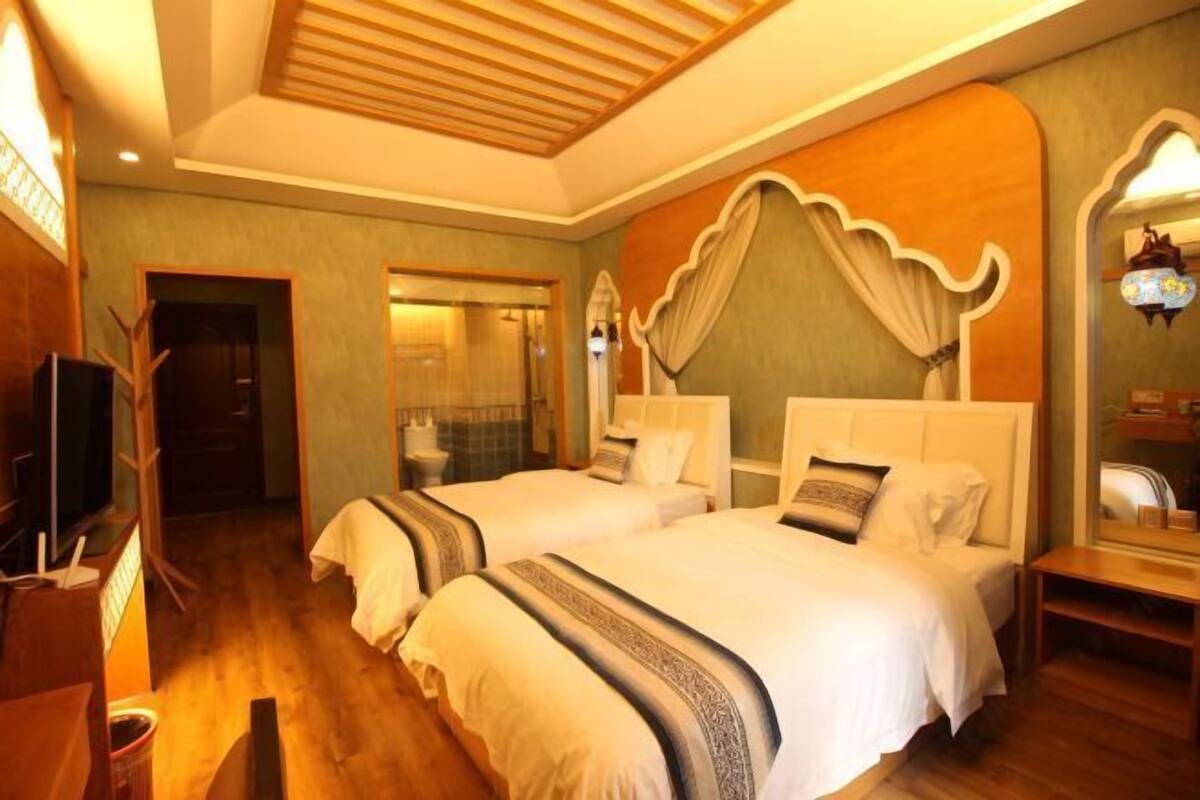 A hotel room with two beds, a television, a desk, and a mirror.