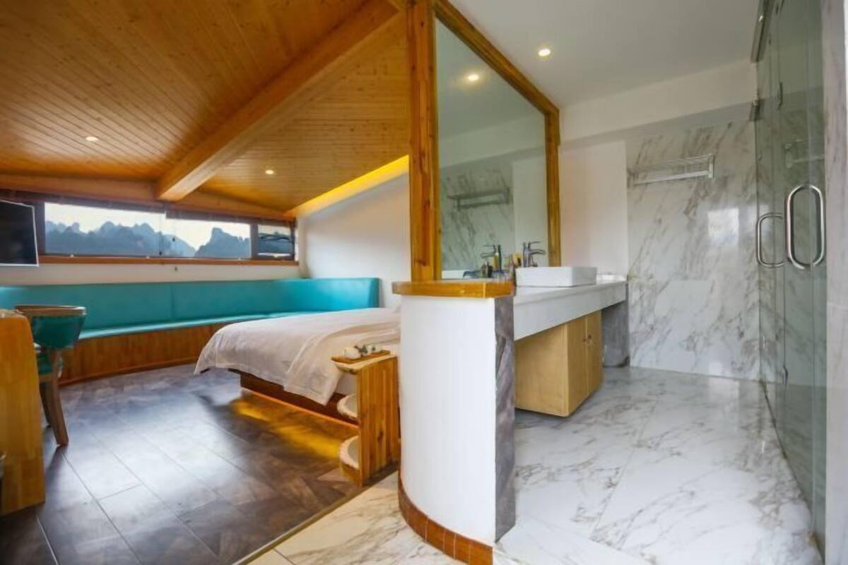 A modern bathroom with a large mirror, marble flooring, and a wooden ceiling.
