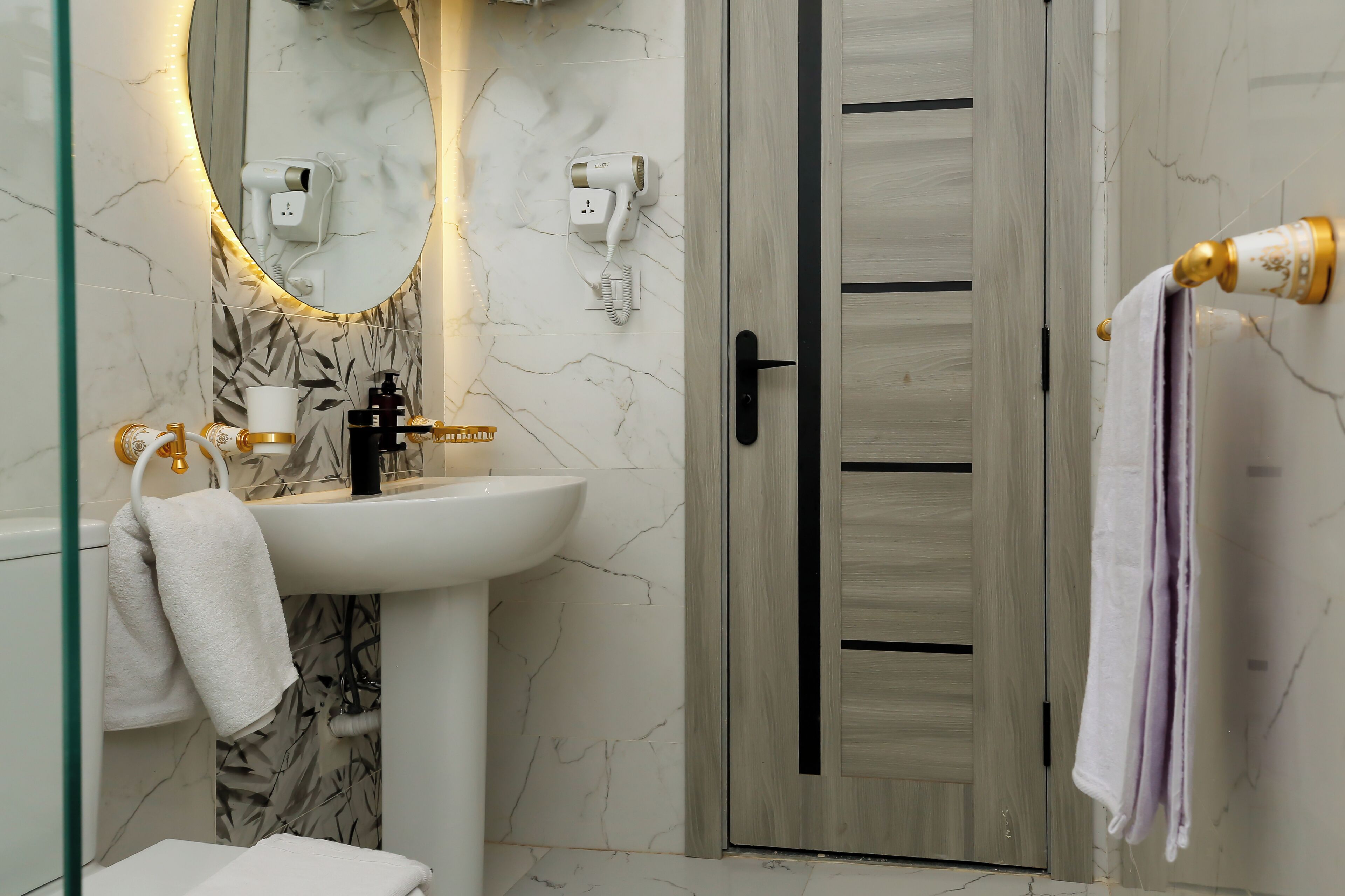 A bathroom with a white sink, a mirror, a hairdryer, and a towel rack.