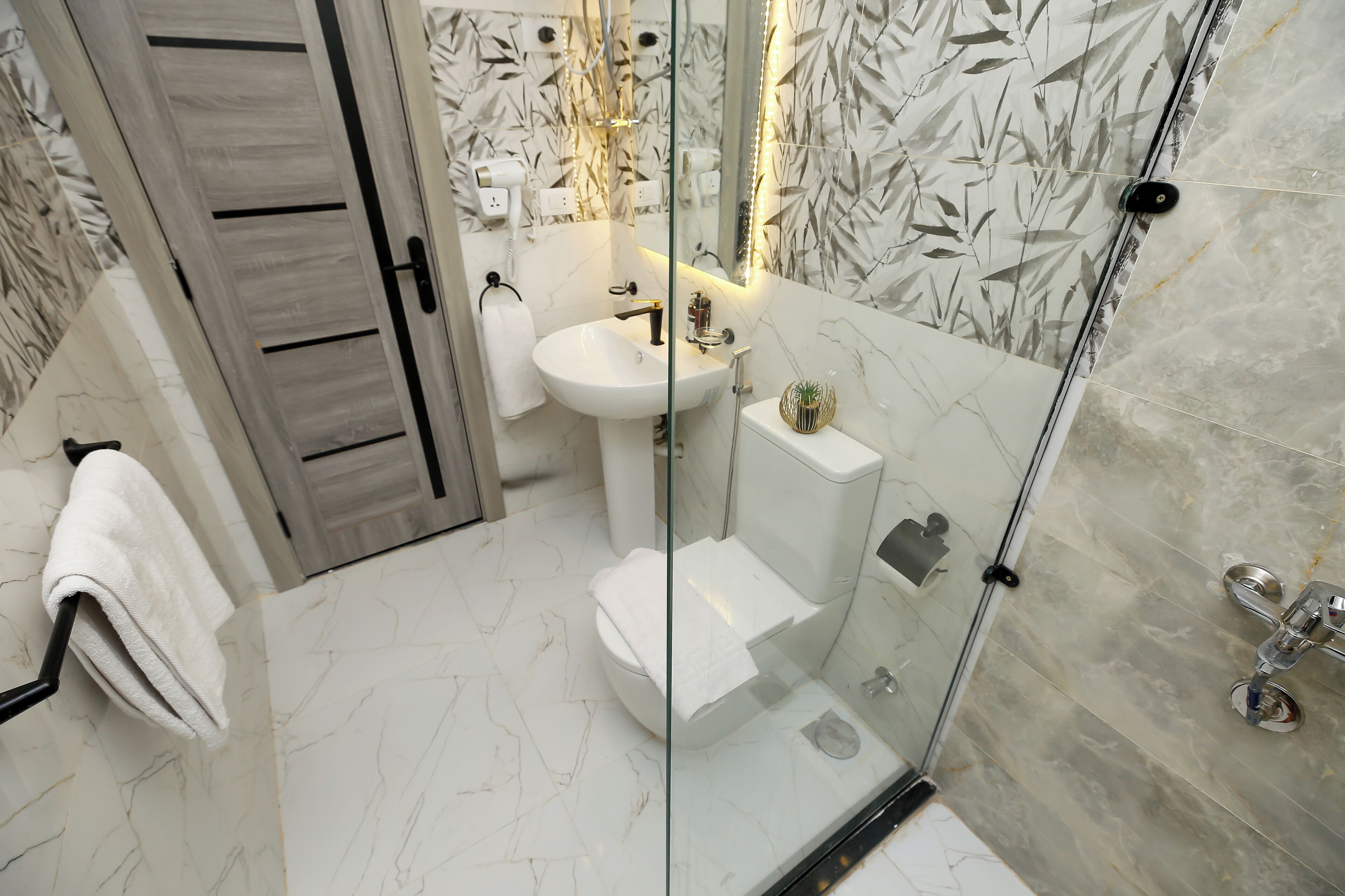 Une salle de bain moderne avec une douche à parois de verre, un lavabo blanc et des toilettes.