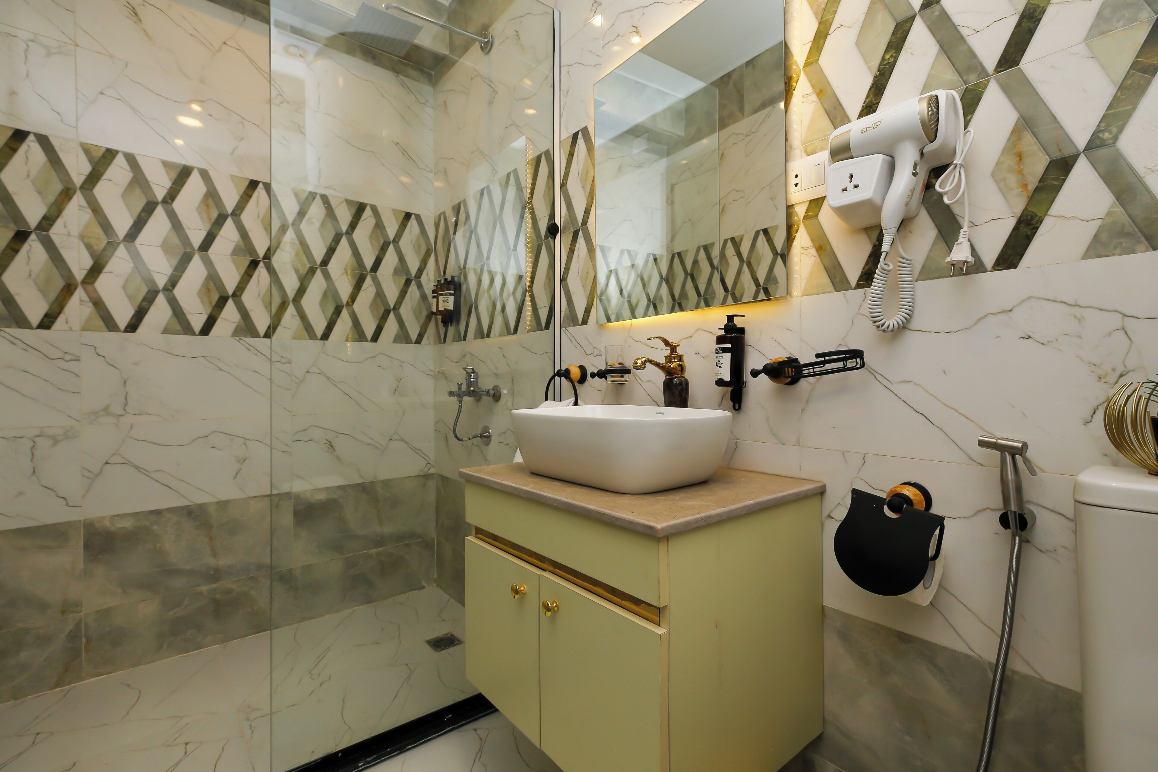 Une salle de bain équipée d’un lavabo, d’un miroir, d’un porte-serviettes et d’un sèche-cheveux fixé au mur.