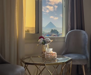 A room with a view of a mountain, a table with a vase of flowers, and a chair. - pyramids palace inn (Giza)