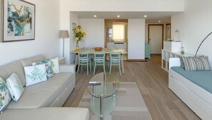 A modern living room with a sofa, a coffee table, and a dining area with chairs and a table.