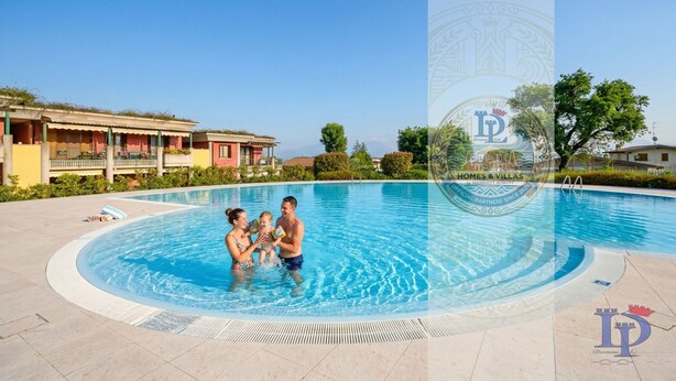 A swimming pool with a family, a clear sky, and a building with a balcony.