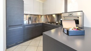 A modern kitchen with grey cabinetry, a stainless steel range hood, and a built-in oven.