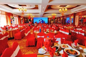 A banquet hall with round tables, red chairs, and chandeliers. - Westqiang Homeland Hotel (Mao County)
