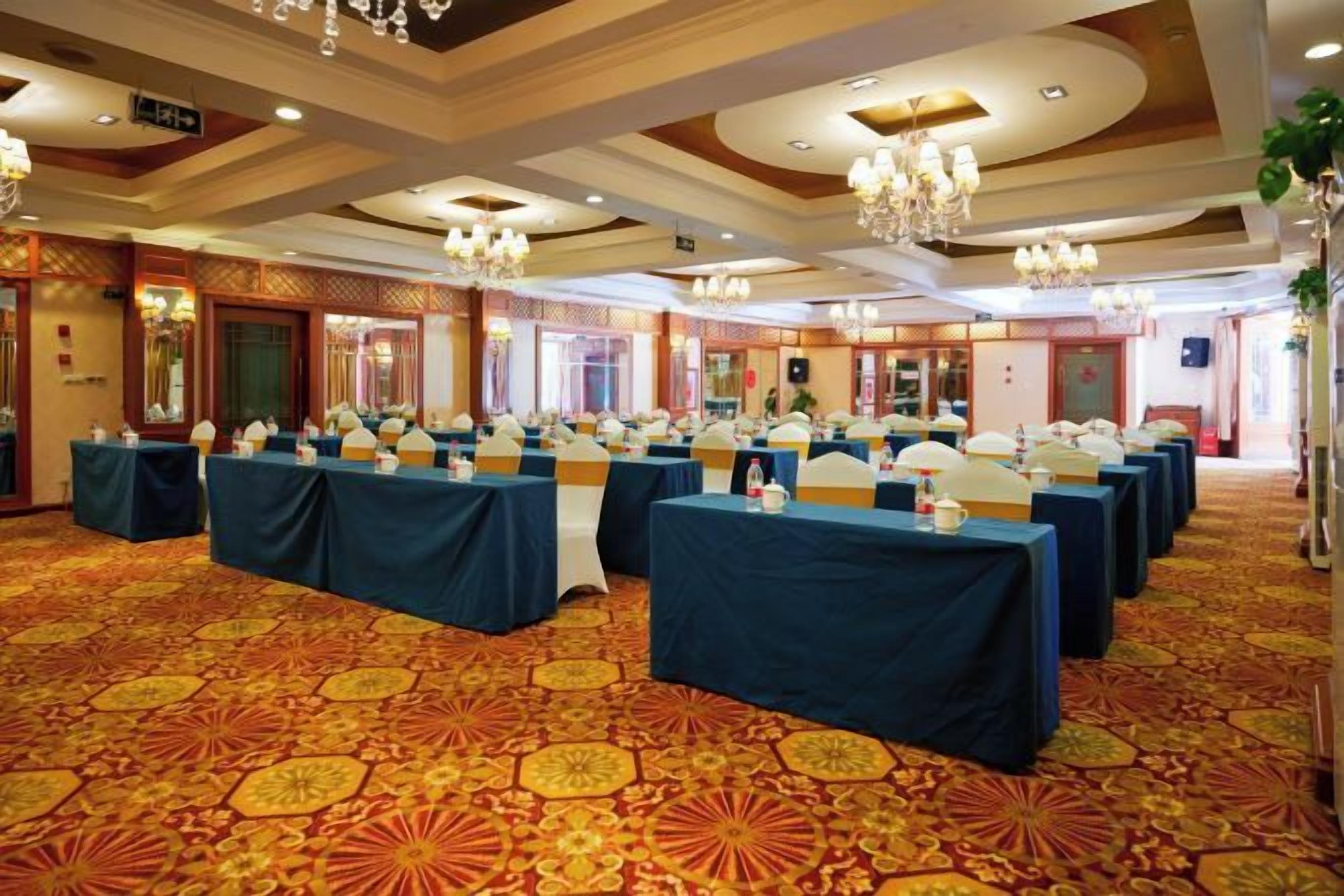 A conference room with multiple tables, chairs, and a patterned carpet.
