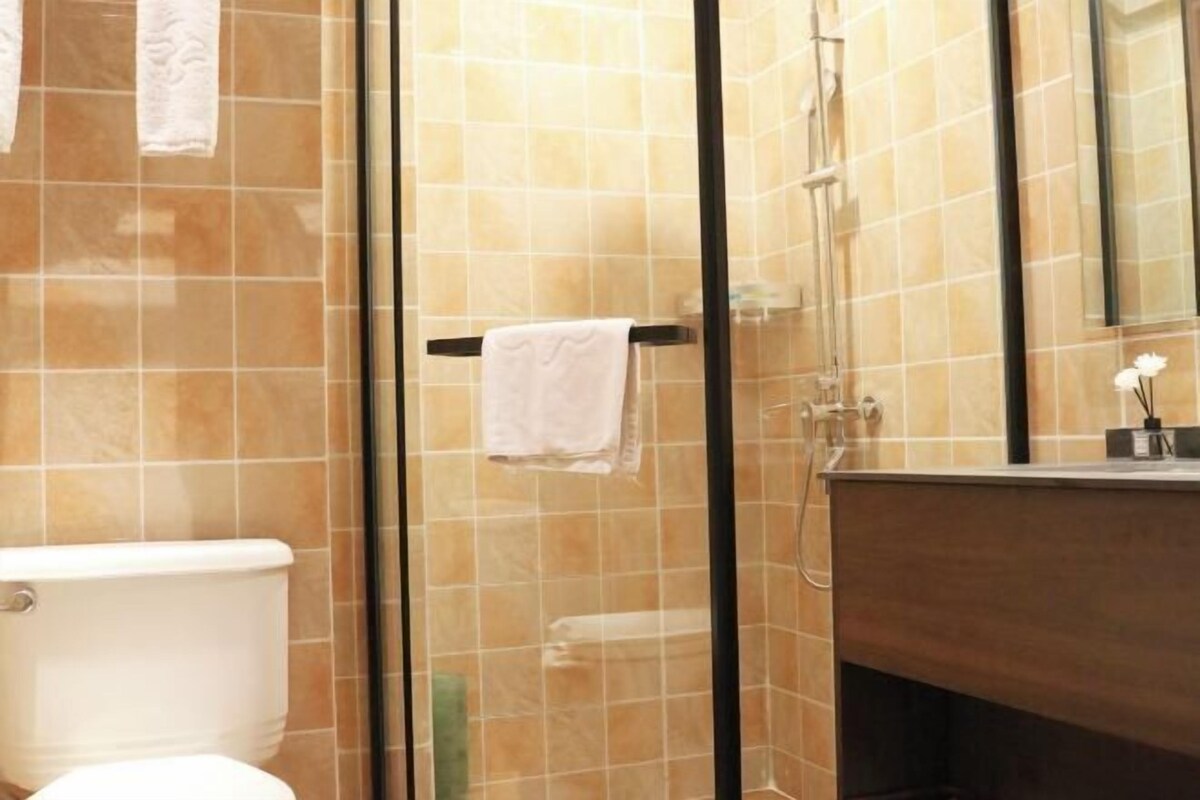 Un baño con cabina de ducha de vidrio, inodoro blanco y tocador de madera.