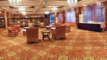 A spacious room with a patterned carpet, multiple seating areas, and a buffet table.