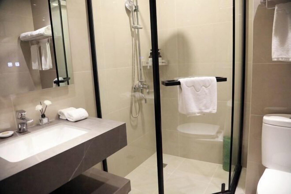 Un baño moderno con ducha de vidrio, lavamanos con espejo e inodoro.