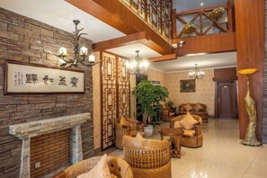 A traditional-style living room with a fireplace, wooden furniture, and a large plant.