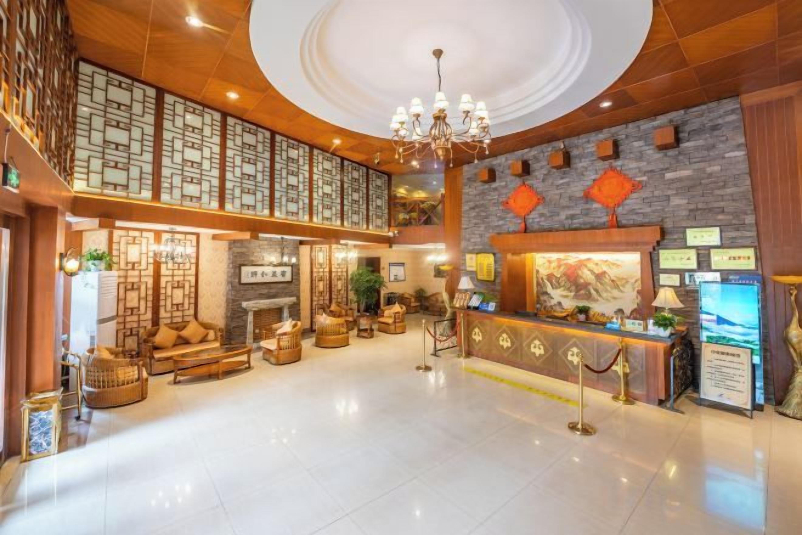 A hotel lobby with a reception desk, seating area, and a chandelier.