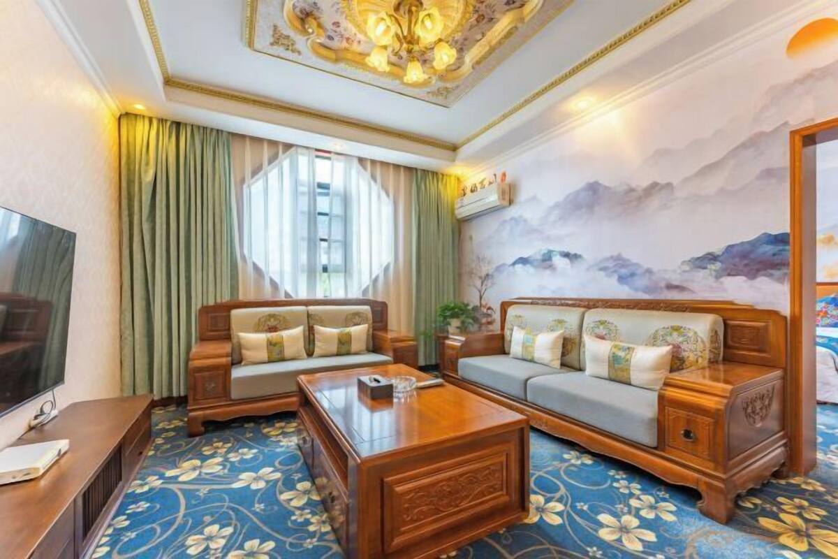 A hotel room with a large sofa set, a coffee table, a flat-screen TV, and a mural on the wall.
