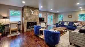 A living room with a stone fireplace, a blue sofa set, and a wooden coffee table. - Creekside, spacious home for 8; 9 mi. Highlands, close Sky Valley, GA (Scaly Mountain)