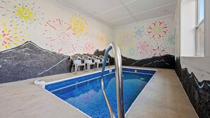 An indoor swimming pool with a mural of fireworks and mountains on the walls.